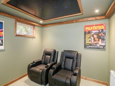 A room with two black recliner chairs and a pulp fiction poster on the wall at 1 Valley View in Lanreath