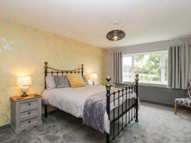 A bedroom with a metal bed frame bedside tables lamps and a window with curtains at Pool House in The Narth near Trellech