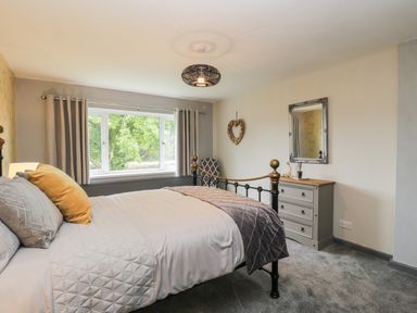 A bedroom with a bed next to a window a dresser with a mirror and a chair at Pool House in The Narth near Trellech
