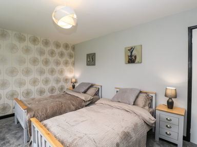 A bedroom with two single beds bedside tables with lamps and animal paintings on the walls at Pool House in The Narth near Trellech