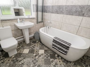 A bathroom with a toilet sink bathtub and patterned floor tiles at Pool House in The Narth near Trellech
