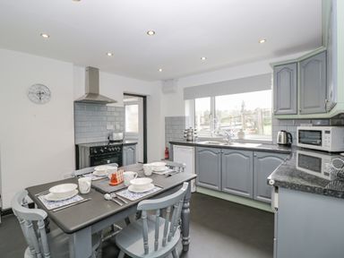 A kitchen with a dining table set for four and grey cabinets at Pool House in The Narth near Trellech