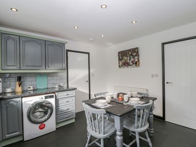 A kitchen with gray cabinets a dining table set with dishes and four chairs at Pool House in The Narth near Trellech