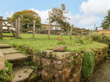 A garden area with stone steps and a wooden fence in the background at Pool House in The Narth near Trellech