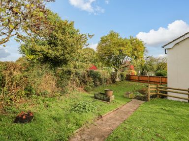 A garden path leading past a tree and flower pots next to a white building at Pool House in The Narth near Trellech