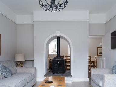 A living room with two grey sofas a wooden coffee table and a black stove in an arched wall at Keepers Cottage in Hawkshead