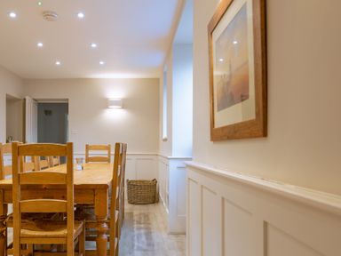 A dining area with a wooden table and chairs a wicker basket and a framed picture at Keepers Cottage in Hawkshead