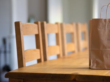 A wooden dining table with wooden chairs and a brown paper bag at Keepers Cottage in Hawkshead