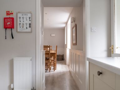 A hallway leading to a dining area with wooden table and chairs at Keepers Cottage in Hawkshead