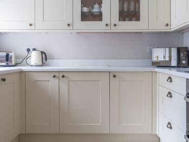 A kitchen with white cabinets a kettle a toaster and a microwave at Keepers Cottage in Hawkshead