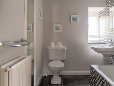 A bathroom with a toilet sink and bathtub with patterned tile at Keepers Cottage in Hawkshead