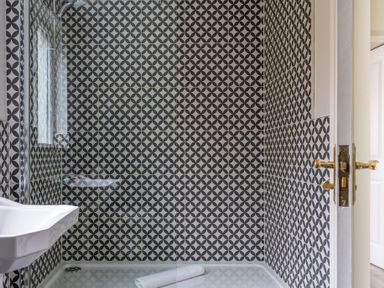 A shower area with a white sink and black and white patterned tiles at Keepers Cottage in Hawkshead