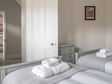 A bedroom with two single beds with folded towels and a chest of drawers at Keepers Cottage in Hawkshead