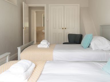 A bedroom with two single beds towels on beds chair and closet doors at Keepers Cottage in Hawkshead