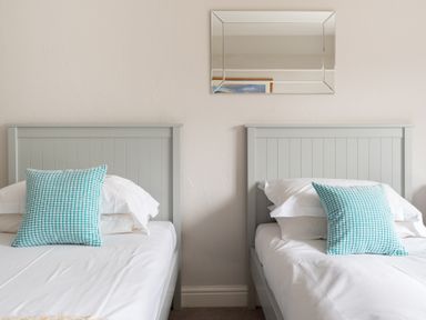 A bedroom with two single beds with gray headboards and blue patterned pillows at Keepers Cottage in Hawkshead