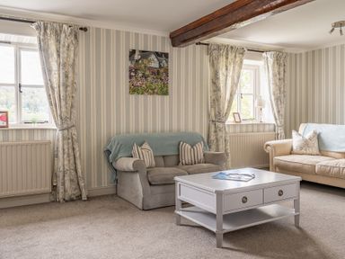 A living room with two sofas a coffee table and two windows with curtains at Grassholme in Hawkshead