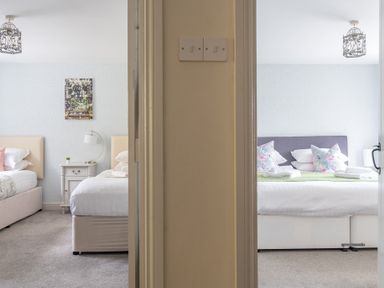Two bedrooms separated by a wall each with a bed bedside table and light fixture at Grassholme Hawkshead