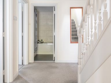 A hallway with carpeted floor stairs and a bathroom visible through an open door at Grassholme in Hawkshead