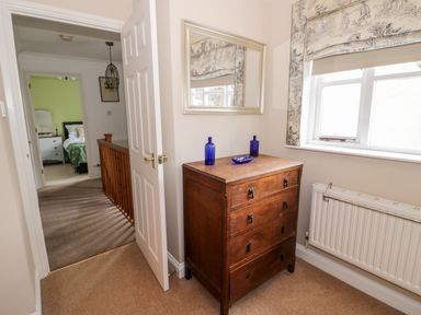 A hallway with a wooden chest of drawers and a mirror above it at Rosemead in Moreton-In-Marsh