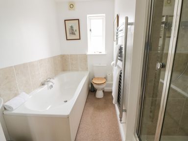 A bathroom with a bathtub toilet shower and towel rack at Rosemead in Moreton-In-Marsh