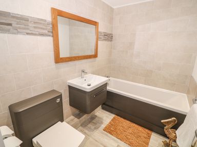 A bathroom with a toilet sink bathtub and mirror at Bay View in Trearddur Bay