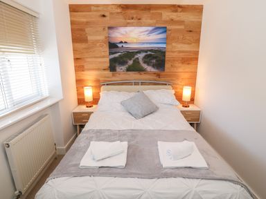 A bedroom with a double bed bedside tables lamps and a window at Bay View in Trearddur Bay