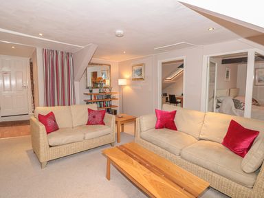 A living room with two beige sofas red pillows wooden coffee table and bookshelf at Manor Studio in Dartmouth