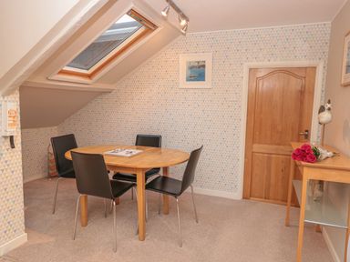 A dining area with a wooden round table and four black chairs under a skylight at Manor Studio in Dartmouth