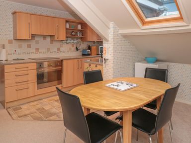 A kitchen with wooden cabinets a built in oven a wooden dining table with four black chairs and a skylight window at Manor Studio in Dartmouth