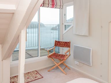 A room with a wooden chair next to a window overlooking a body of water at Manor Studio in Dartmouth