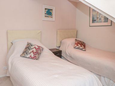 A bedroom with two single beds and patterned cushions at Manor Studio in Dartmouth