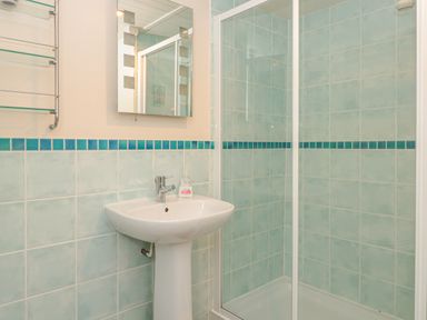 A bathroom with a pedestal sink a mirror glass shower enclosure and tiled walls at Manor Studio in Dartmouth