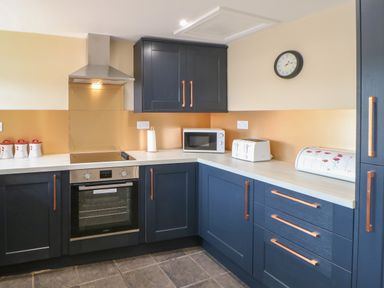 A kitchen with dark blue cabinets white countertop microwave toaster and oven at Crag View in West Woodburn