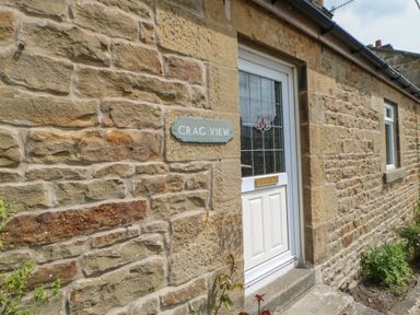 A stone house exterior with a white door and a plaque reading Crag View in West Woodburn