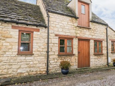 Stone cottage exterior with wooden windows a wooden door and two potted plants at Chapel Cottage in Leonard Stanley near Kings Stanley