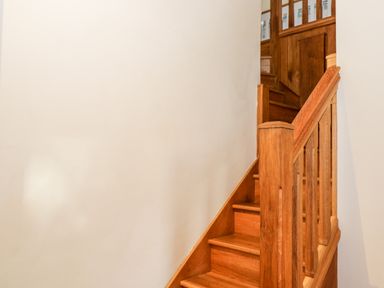 A wooden staircase with railing against a plain white wall at Chapel Cottage Leonard Stanley near Kings Stanley