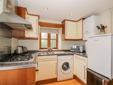 A kitchen with a gas stove sink washing machine microwave and fridge at Chapel Cottage Leonard Stanley near Kings Stanley
