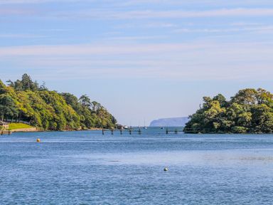 A body of water with trees on both sides and boats in the distance at Sea View Cottage in Menai Bridge