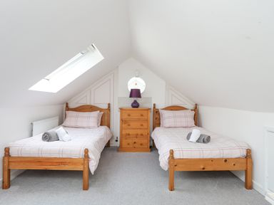 A bedroom with two single beds with wooden frames and a wooden drawer with a lamp in between at Sea View Cottage in Menai Bridge