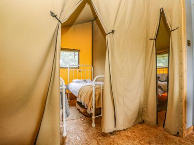 A tent bedroom with metal bed frames and blankets at Honey @ Stars & Embers Glamping in Grampound