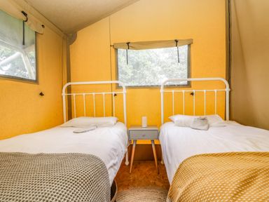A tent bedroom with two single beds a nightstand and two windows at Honey @ Stars & Embers Glamping in Grampound