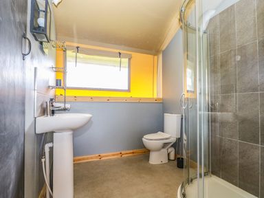 A bathroom with a pedestal sink a toilet and a glass shower enclosure at Honey @ Stars & Embers Glamping in Grampound
