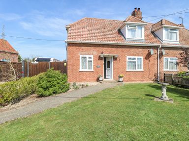 A brick house with a tiled roof and front garden with grass and bushes at Lillies Pad in Methwold near Feltwell