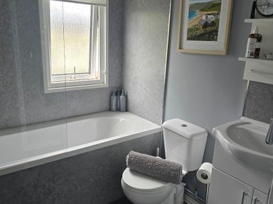 A bathroom with a bathtub and sink at Caban Tywod Abersoch