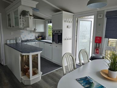A kitchen with cabinets and an island at Caban Tywod in Abersoch