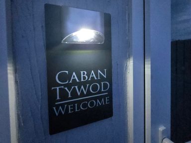 A welcome sign with light at Caban Tywod in Abersoch