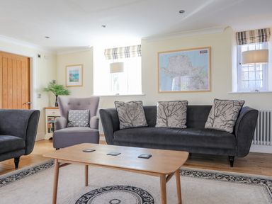 A living room with sofas a wooden coffee table and framed map on the wall at Capel Hermon in Llanynghenedl near Bodedern