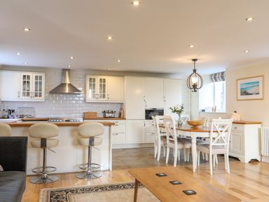 A kitchen with bar stools and a dining table with chairs at Capel Hermon in Llanynghenedl near Bodedern