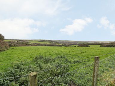 A green fenced field with rolling hills in the background at Underlanes in Boscastle