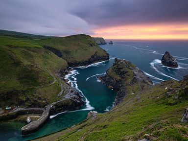 A coastal landscape with cliffs, a small harbor with boats, and a sunset over the ocean at Underlanes in Boscastle